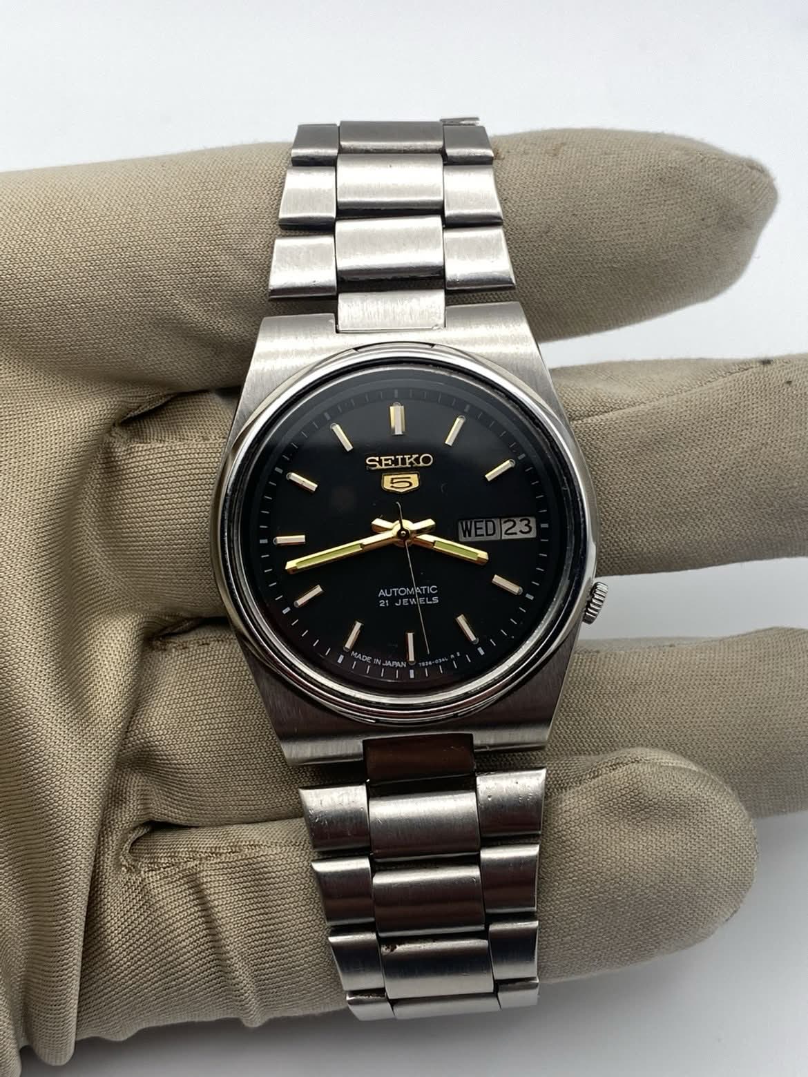 A vintage Seiko 5 held in a gloved hand