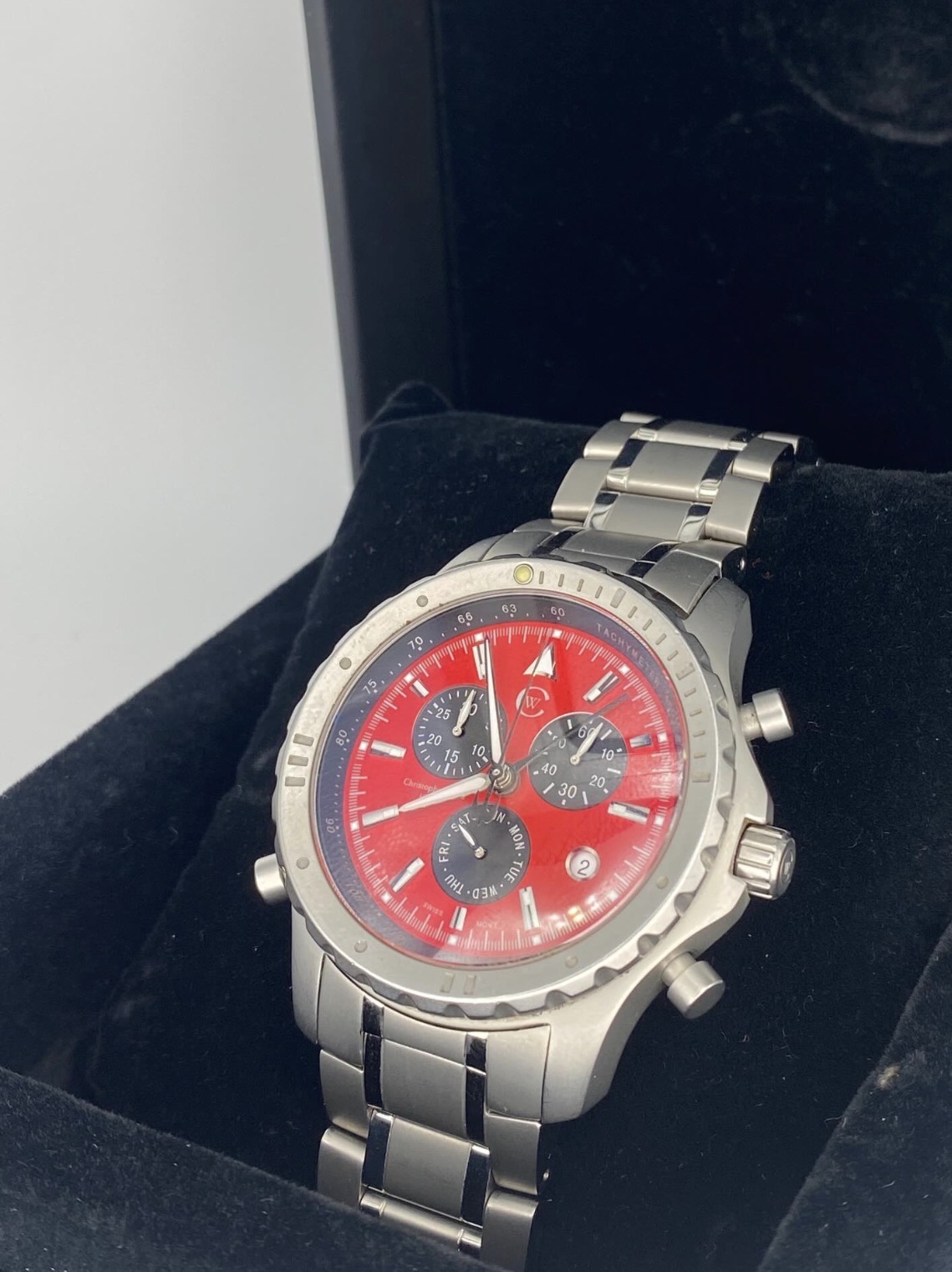 A stainless chronograph presented on a dark cushion inside its presentation box